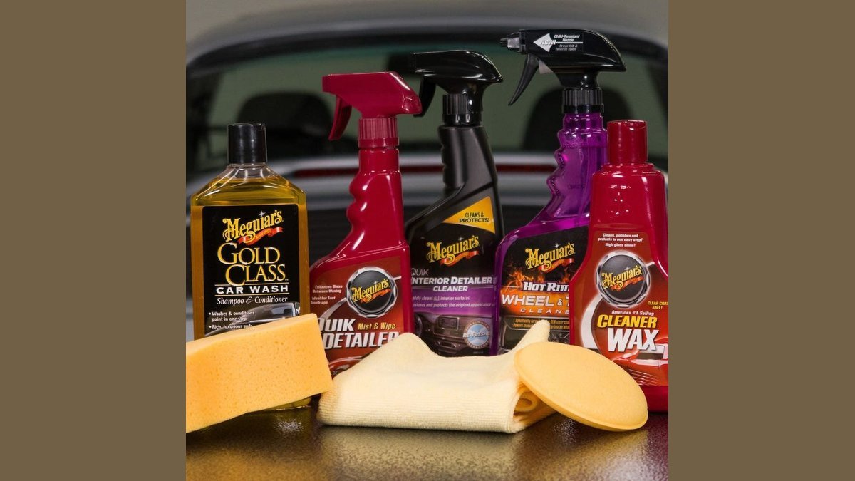 Beginner car detailing kit arranged on driveway next to a clean vehicle.