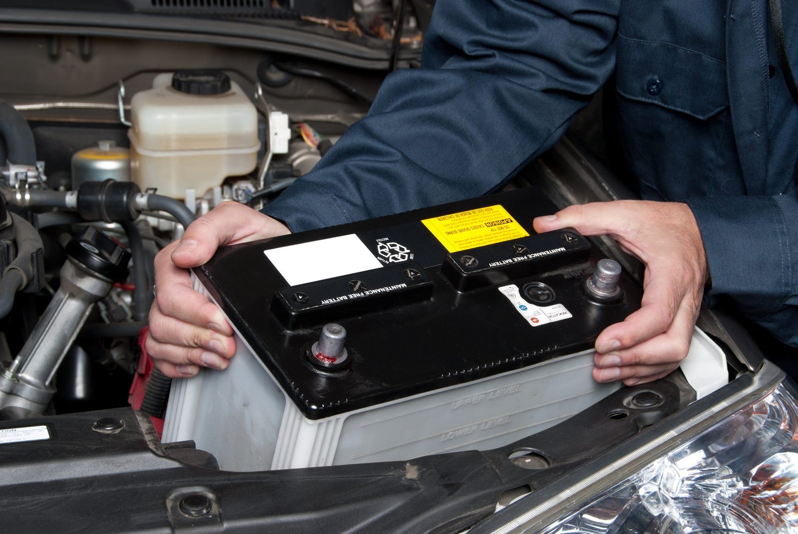 Clean car battery with secure terminals sitting in a vehicle engine bay.