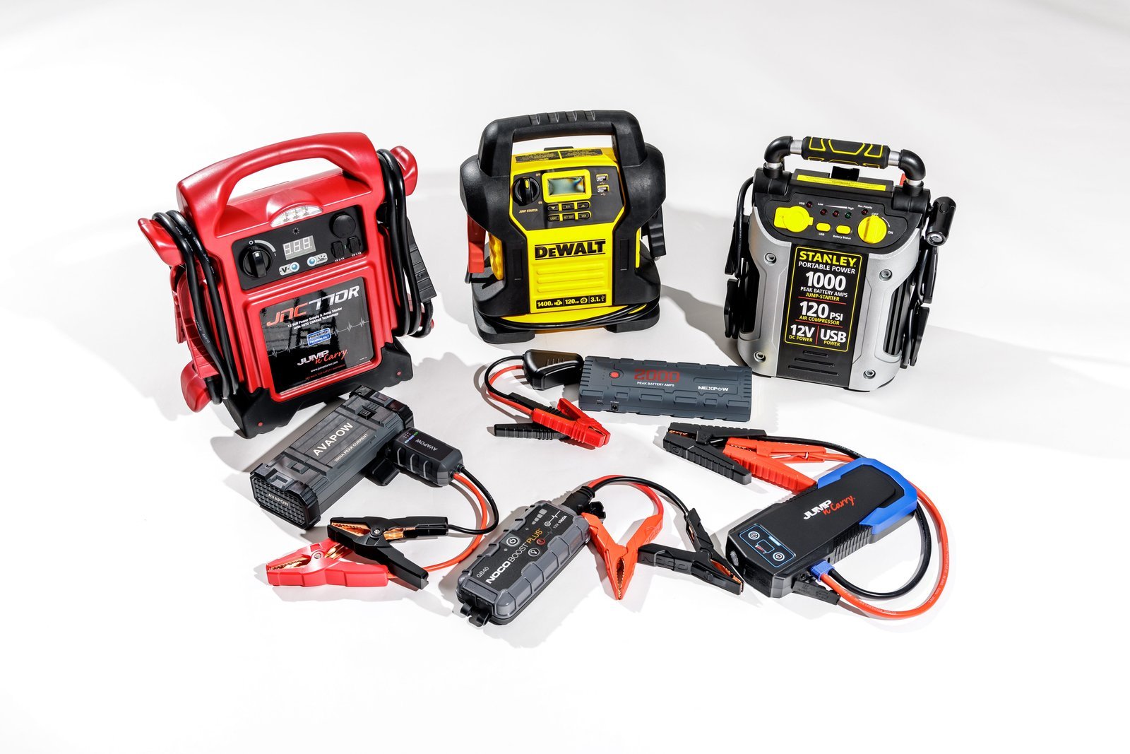 Compact portable car jump starter resting on an open car hood near a battery.