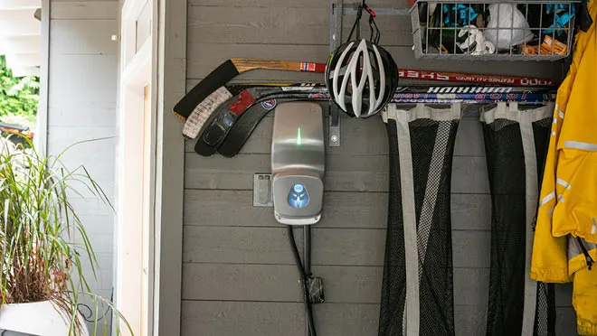 Electrician installing hardwired EV charger connections near a home electrical panel.
