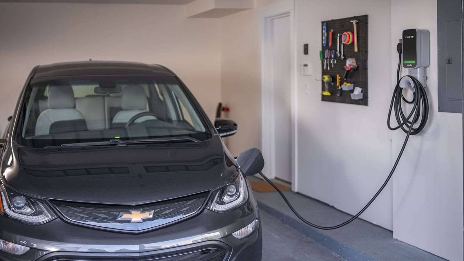 Modern electric vehicle charging in a clean home garage with a wall mounted charger.